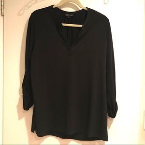 Black v-neck blouse with rolled up sleeves.